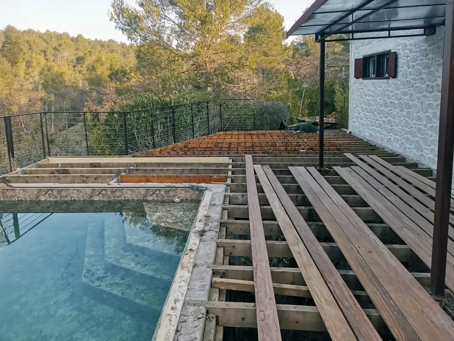 Chantier extérieur de construction d'une terrasse en bois autour d'une piscine