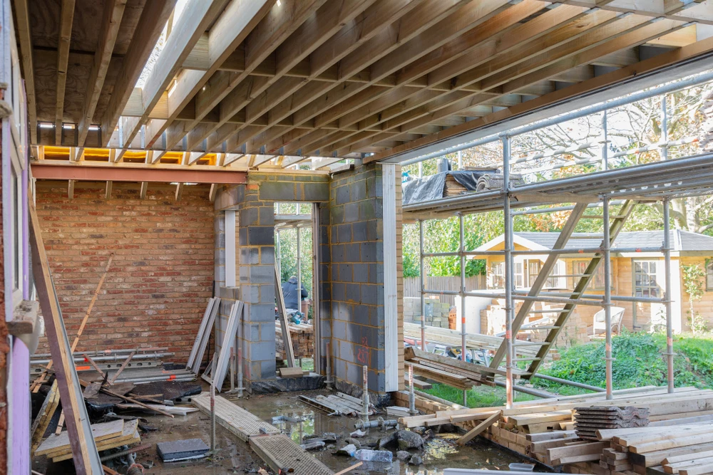 Chantier de construction résidentielle en cours avec ouvriers travaillant sur structure bois et maçonnerie
