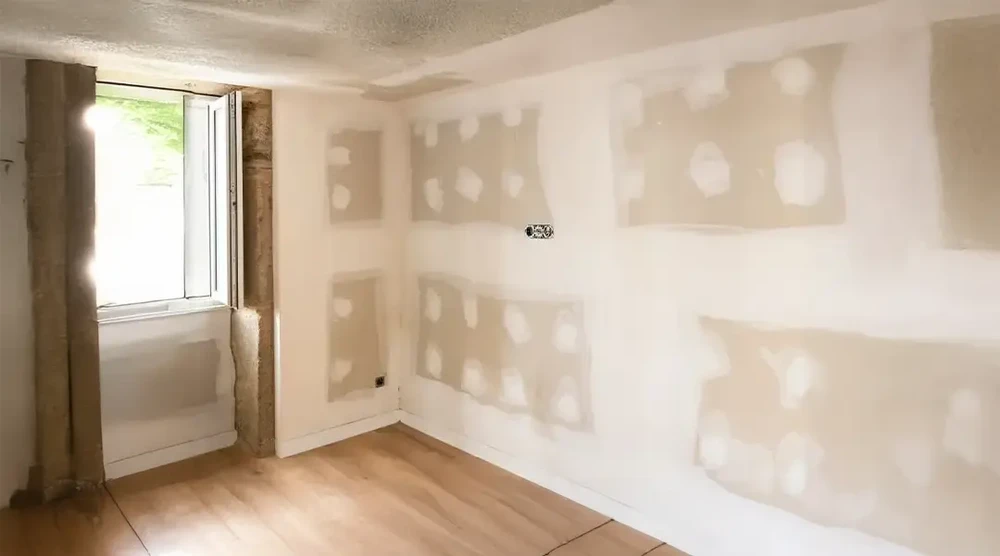 Intérieur de maison en cours de rénovation avec murs en plaques de plâtre jointées mais non peintes