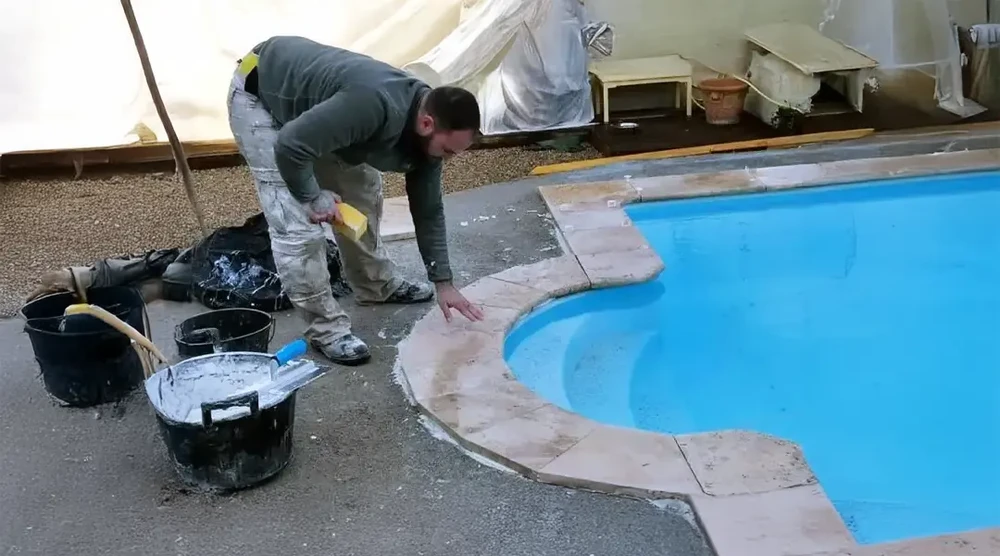 Ouvrier effectuant la rénovation du contour d'une piscine extérieure