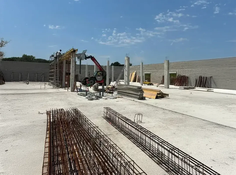 Chantier de construction en extérieur avec ouvriers installant des coffrages sur structure béton