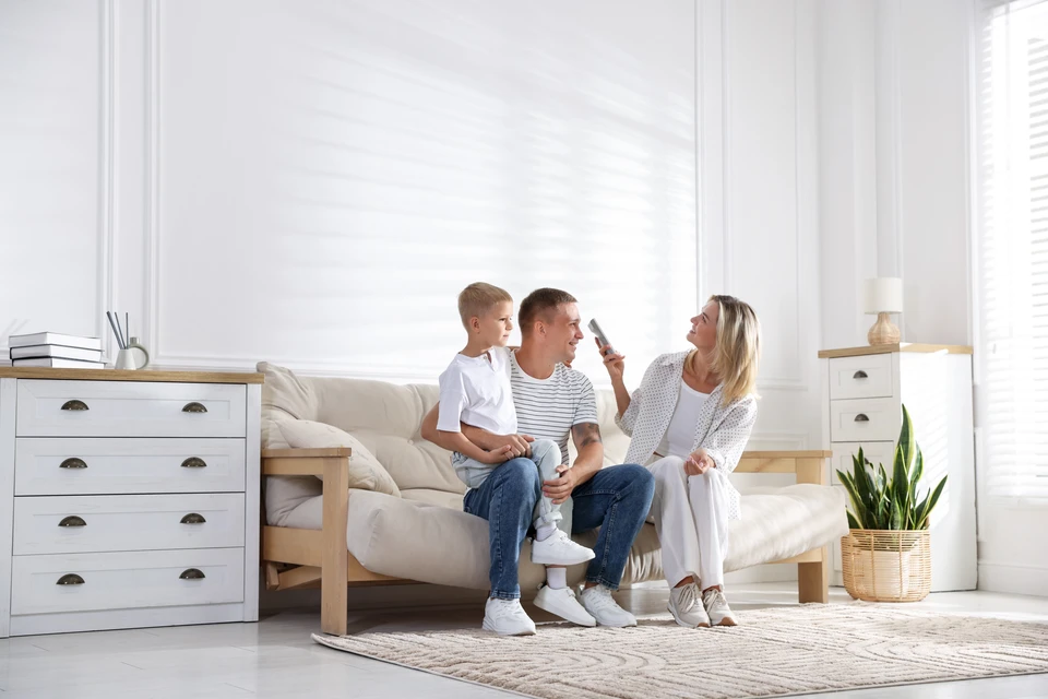Ouvrier en bâtiment appliquant de l'enduit sur un mur intérieur avec une truelle, portant un casque de chantier jaune et une chemise à carreaux