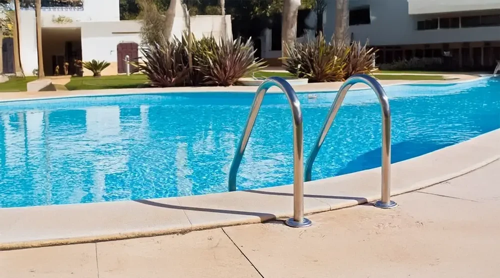 Terrasse extérieure en bois avec piscine à débordement dans environnement boisé