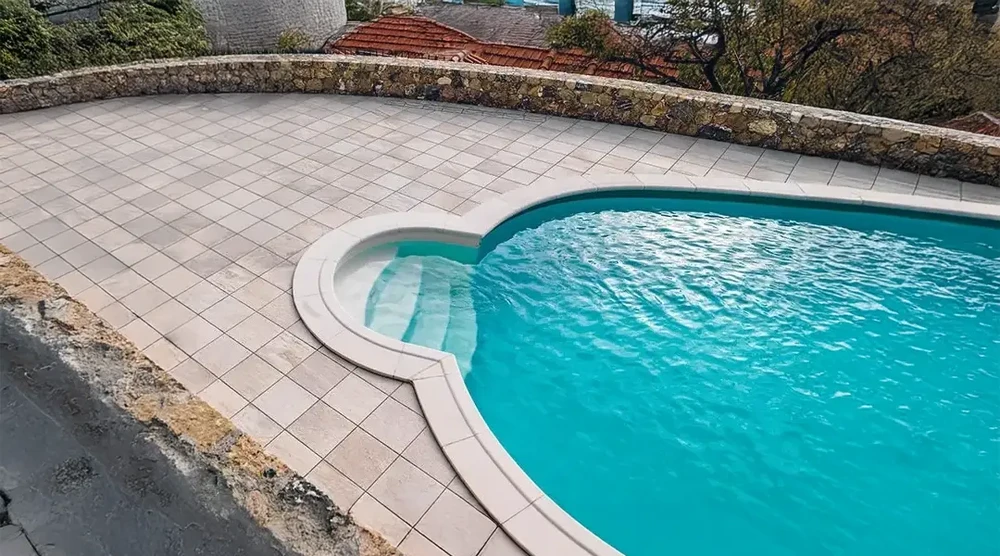 Jardin extérieur moderne avec bassin rectangulaire en béton blanc, palmiers et aménagement paysager minéral